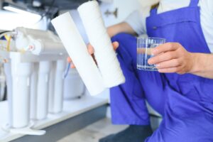 Plumber installs or change water filter Replacement aqua filter Repairman installing water filter cartridges in a kitchen Installation of reverse osmosis water purification system