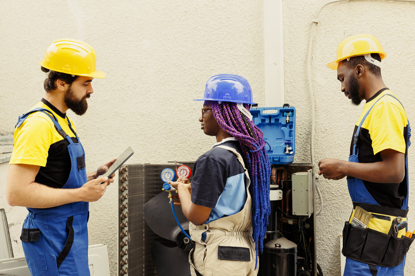 HVAC technicians discussing repairs with tools and equipment, emphasizing professional HVAC services for home comfort maintenance.