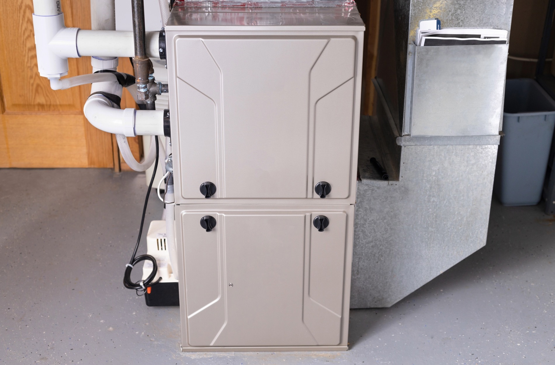 Furnace unit with visible pipes and connections, indicating potential maintenance needs for home heating systems.
