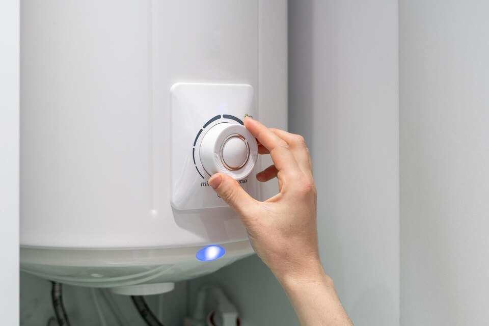 Hand adjusting the temperature dial on a water heater, emphasizing maintenance for optimal performance and longevity.